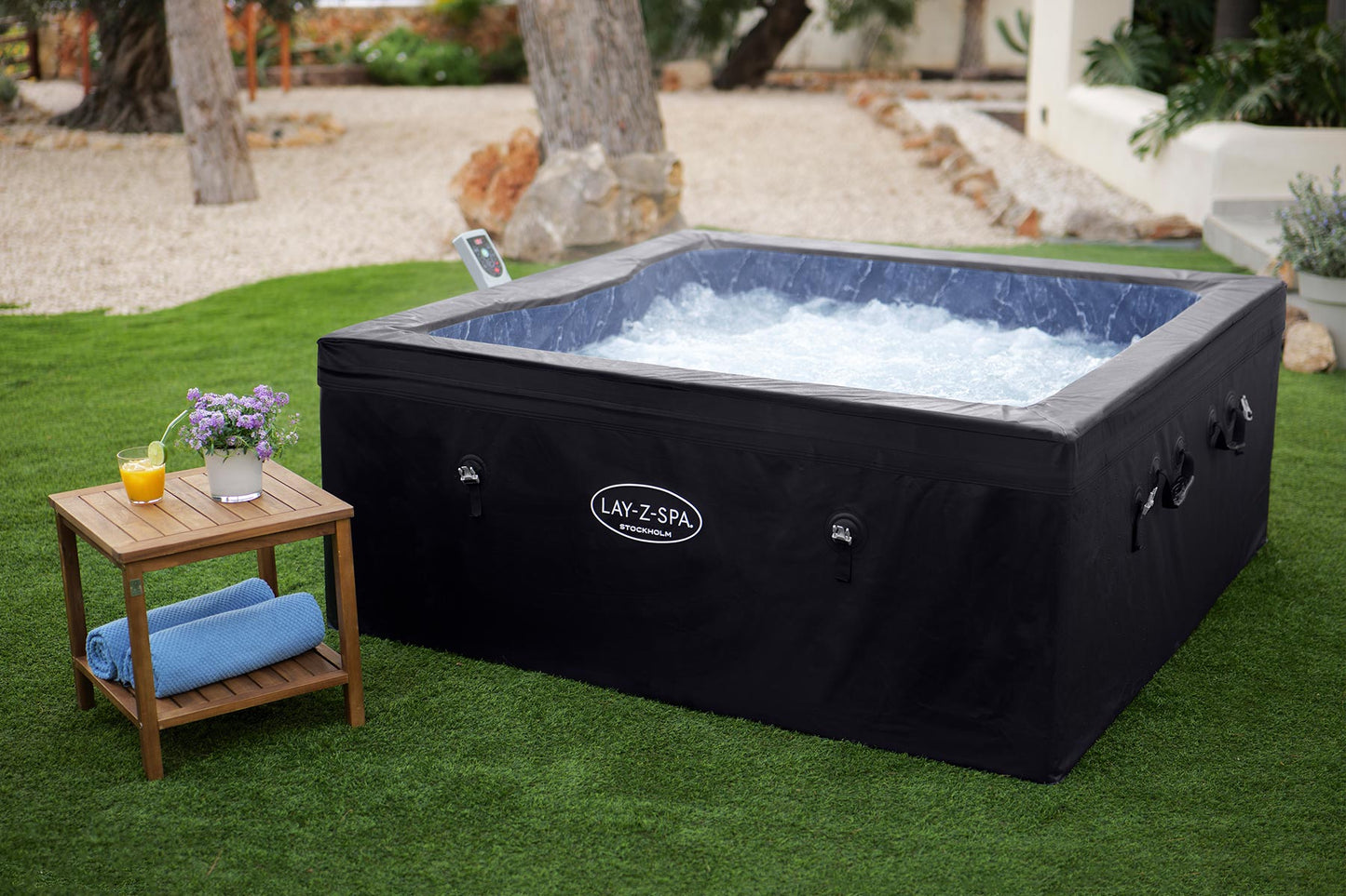 Hot tub with black cover on grass, small table with items nearby