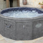 Gray Lay-Z-Spa hot tub on a patio with outdoor furniture and plants.