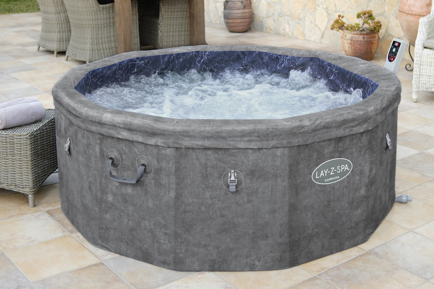 Gray Lay-Z-Spa hot tub on a patio with outdoor furniture and plants.