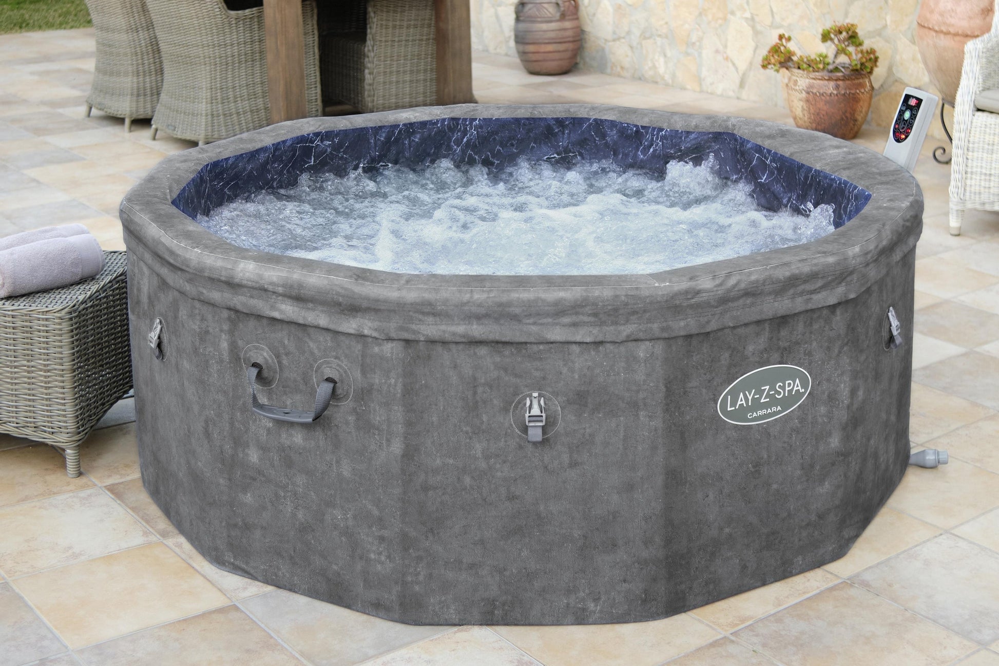 Gray Lay-Z-Spa hot tub on a patio with outdoor furniture and plants.