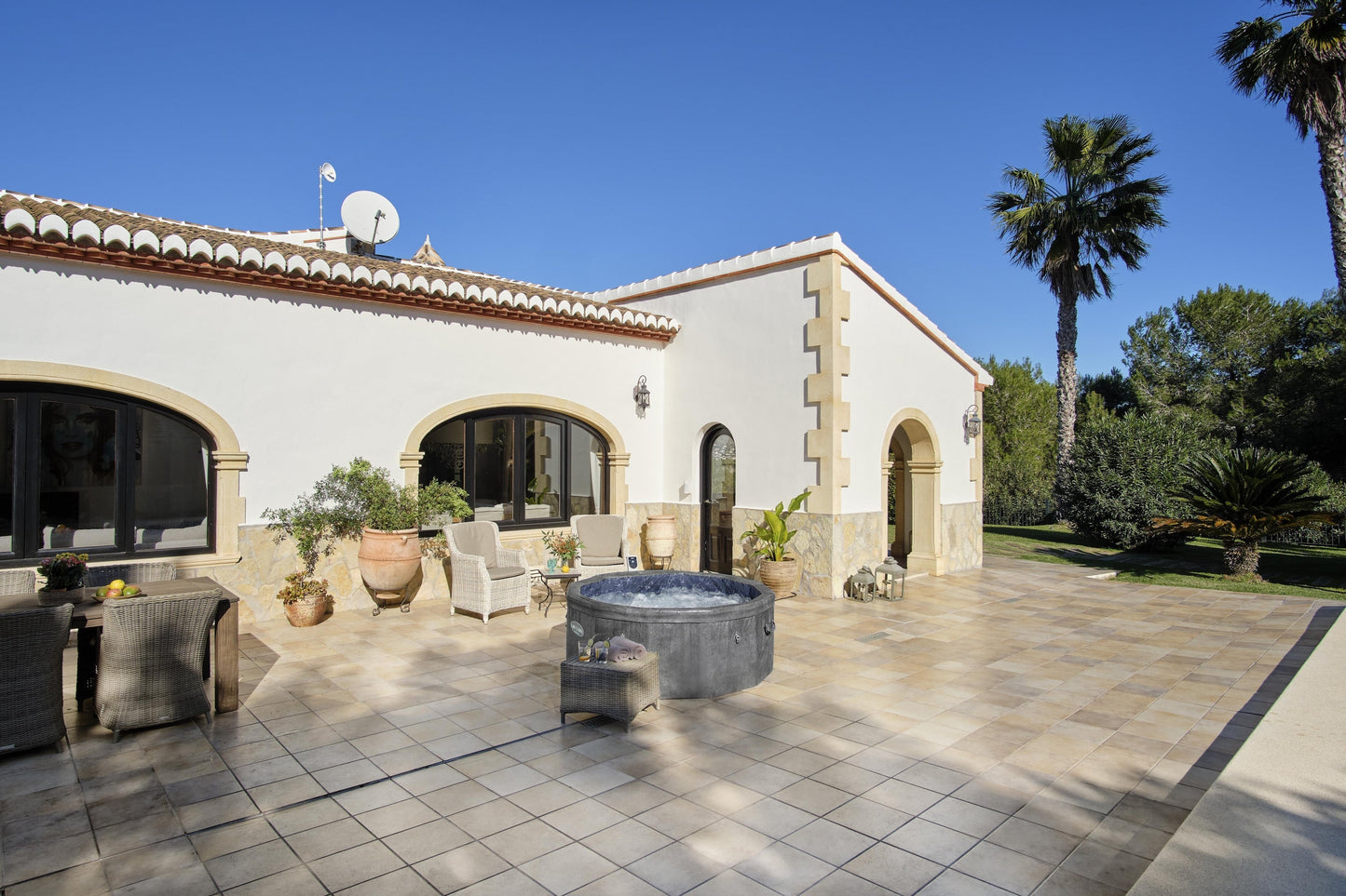 Outdoor patio area of a villa with a pool, chairs, and palm trees.