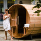 Woman standing next to a Audra wooden outdoor sauna with towels inside