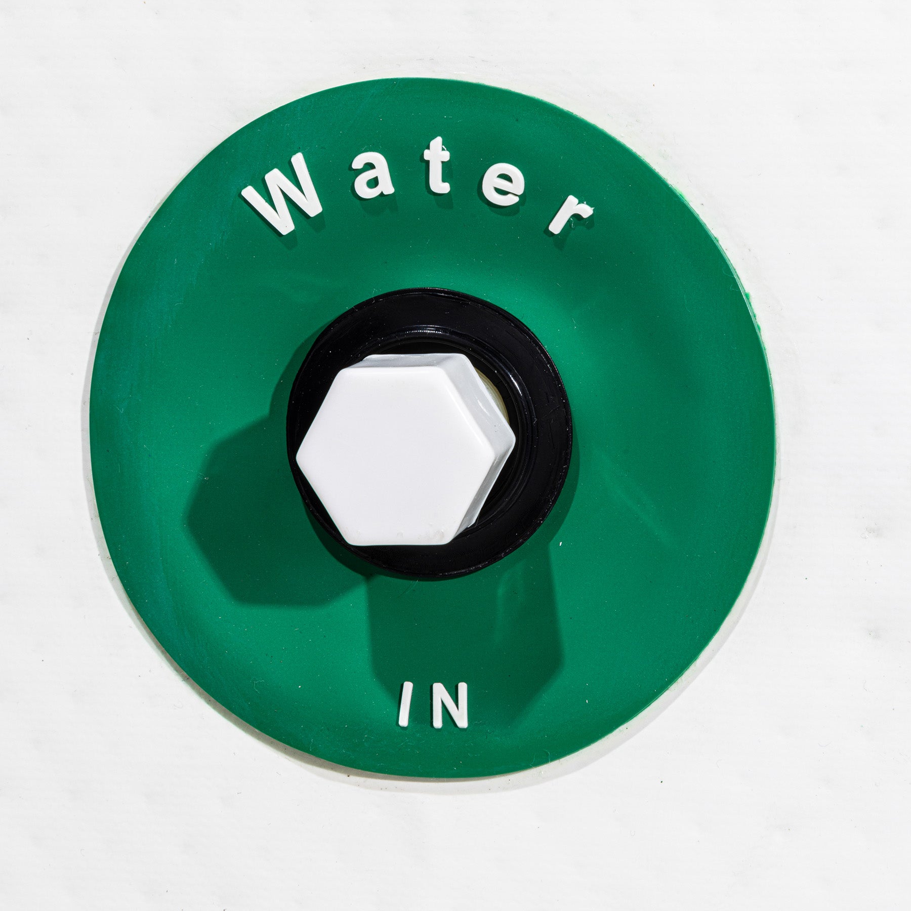 Green valve cover with 'Water In' text on a white background
