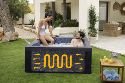 Two people in a portable hot tub with a patio and garden in the background