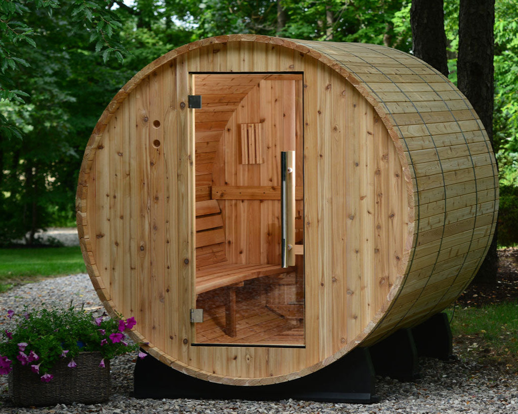 Princeton Wooden barrel-shaped sauna in a natural setting with trees and flowers.