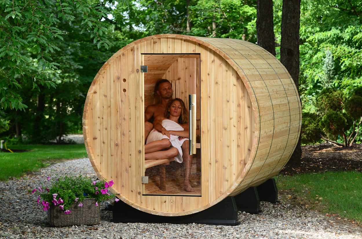 Wooden Princeton outdoor sauna with people inside, surrounded by greenery