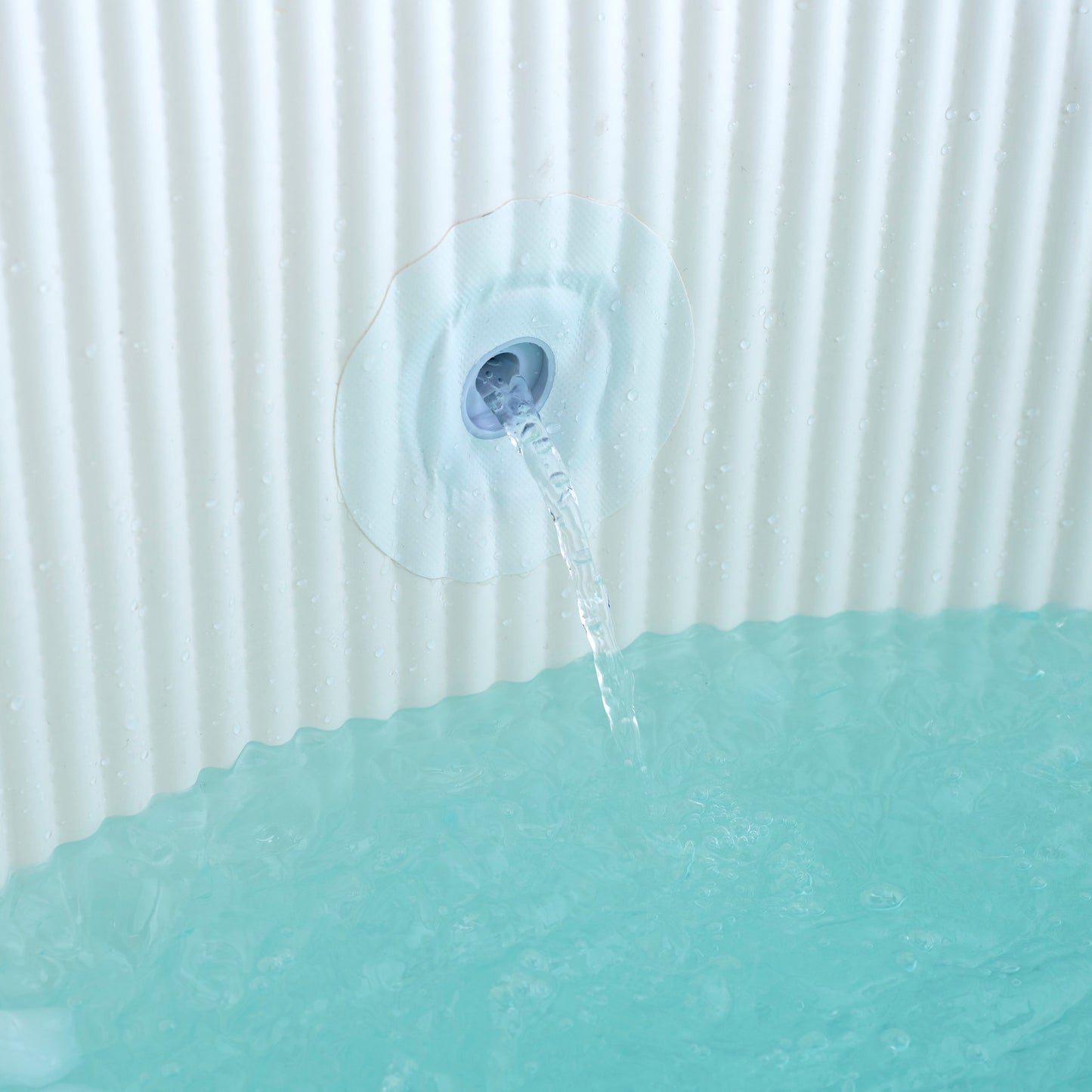 Water fountain with water flowing into a green container against a white background