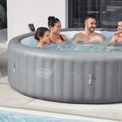Inflatable hot tub with 'Lay-Z-Spa' branding, people enjoying it outdoors.