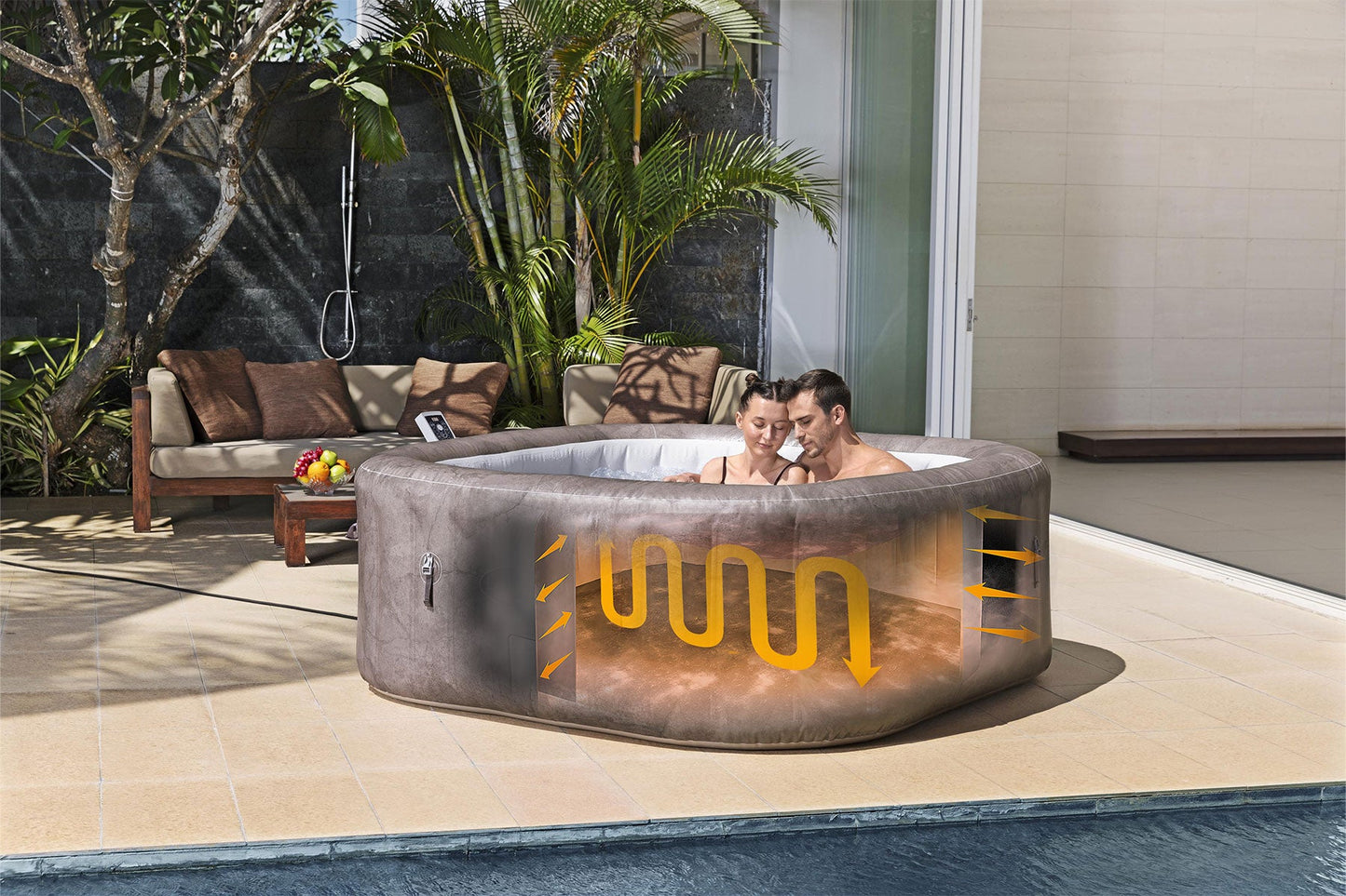 Two people in a hot tub with visible water circulation system, surrounded by outdoor furniture and plants.