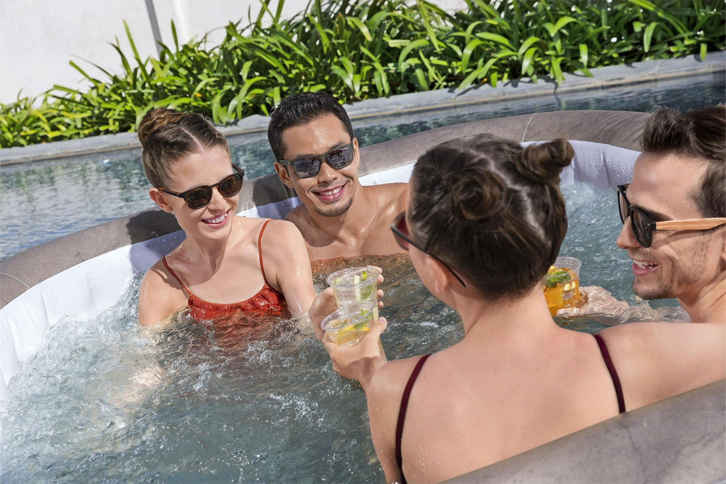 Four people in a hot tub enjoying drinks together