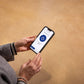 Person holding a smartphone with a loading app on a beige background