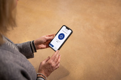 Person holding a smartphone with a loading app on a beige background