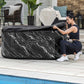 Woman opening a black marble-patterned hot tub on a patio by a pool.