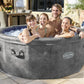 Family of four in a Lay-Z-Spa hot tub outdoors on a sunny day.