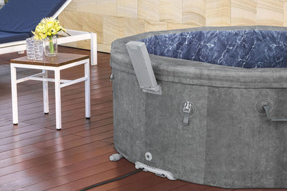 Gray hot tub on a wooden deck with a small table and flowers in the background.