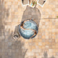 Top-down view of a person relaxing in a hot tub on a tiled patio.