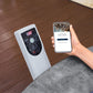 Person using a smartphone app to control an air conditioner with a remote on a wooden floor.