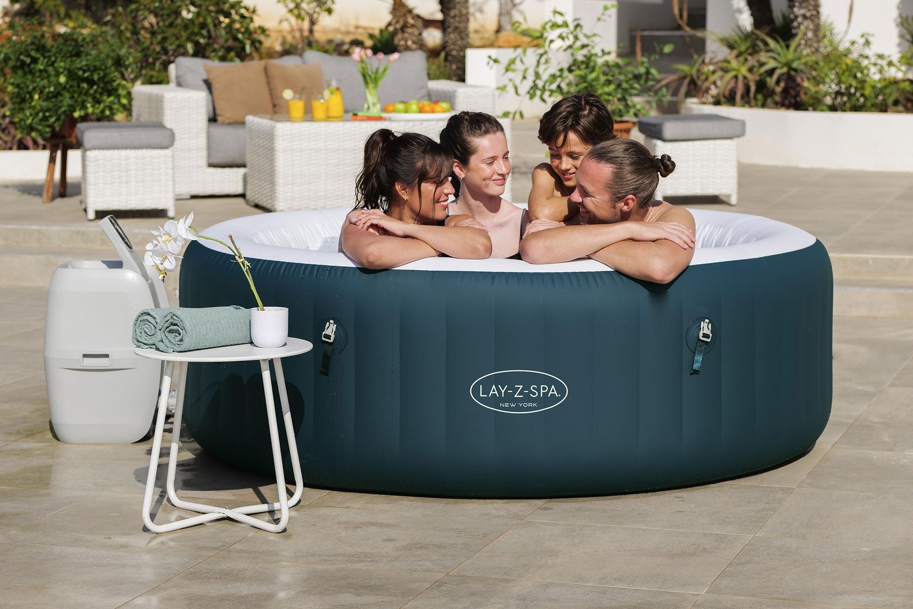 Inflatable hot tub with 'Lay-Z-Spa' branding, people around it, and outdoor setting.