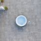 Top-down view of a hot tub on a stone patio with plants and furniture around.