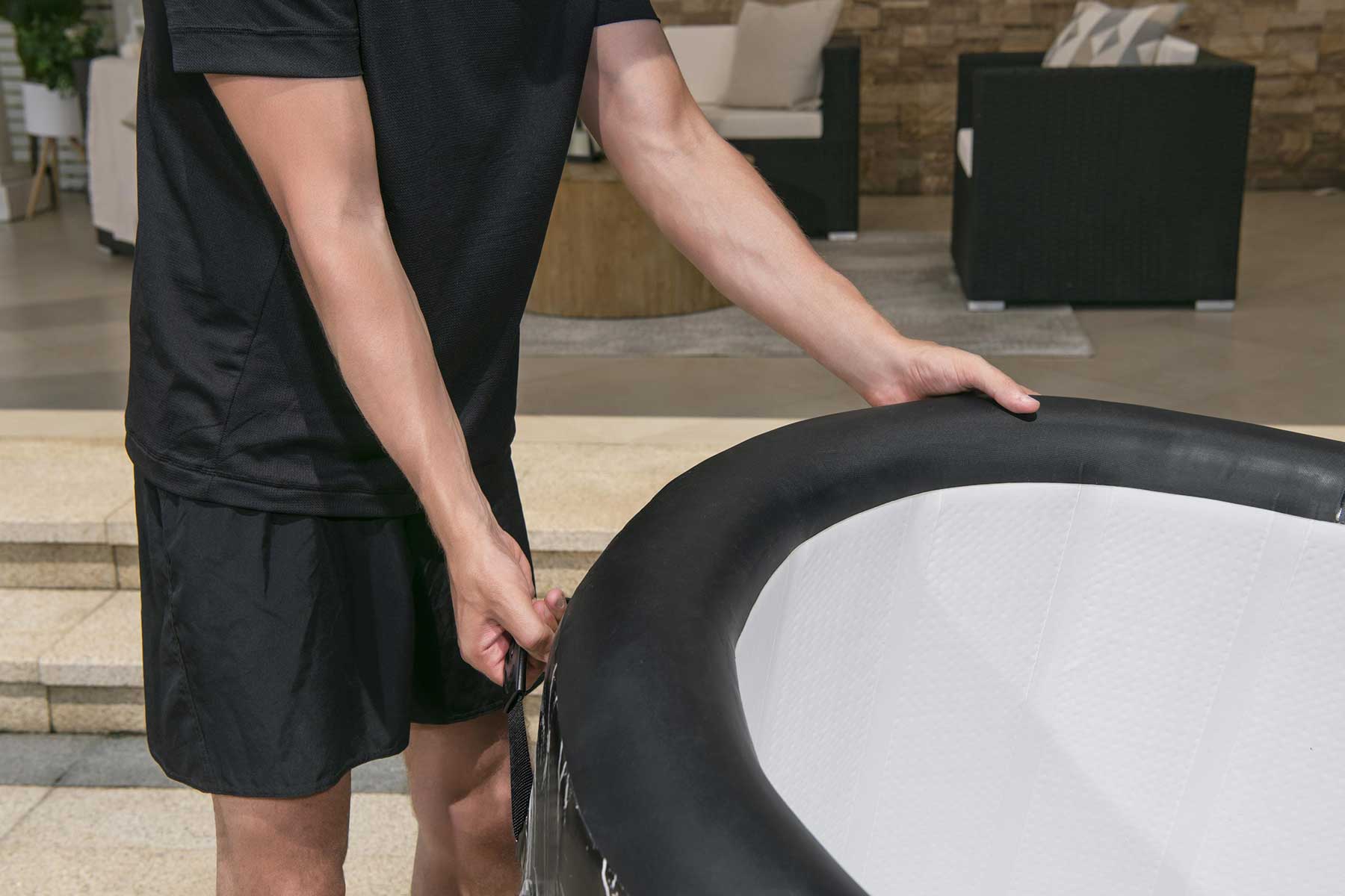 Person holding a hot tub cover outdoors on a patio