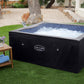Hot tub with black cover on grass, small table with items nearby