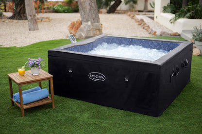 Hot tub with black cover on grass, small table with items nearby