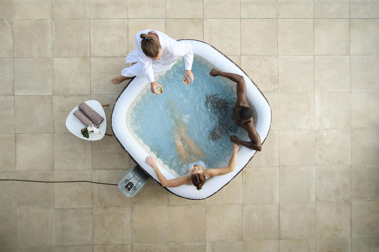 Two people in a hot tub with a person attending to them, viewed from above.