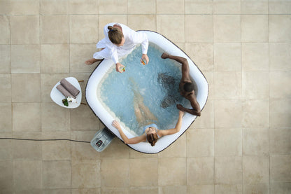 Two people in a hot tub with a person attending to them, viewed from above.