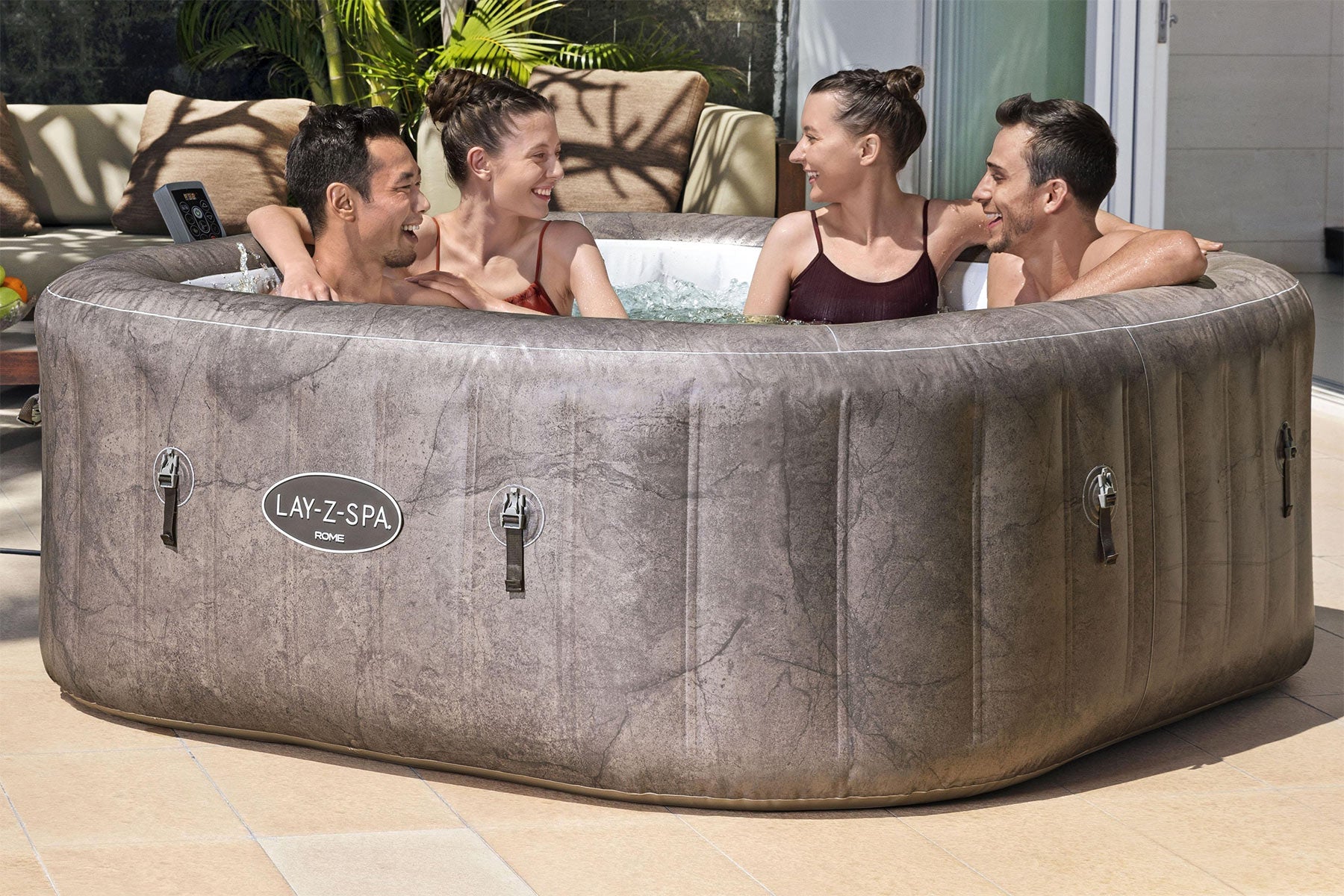 People enjoying a hot tub on a patio with a visible Lay-Z-Spa brand.