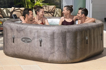 People enjoying a hot tub on a patio with a visible Lay-Z-Spa brand.